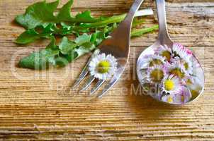 gänseblümchen auf einer gabel auf holzhintergrund