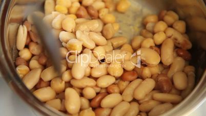Turning mix of boiling beans in a pot