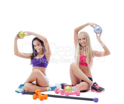 Two smiling young female athletes posing in studio