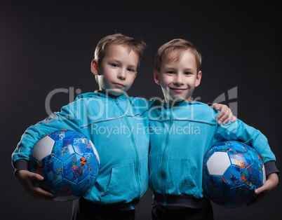 Portrait of smiling twin boys posing with balls