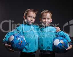 Portrait of smiling twin boys posing with balls