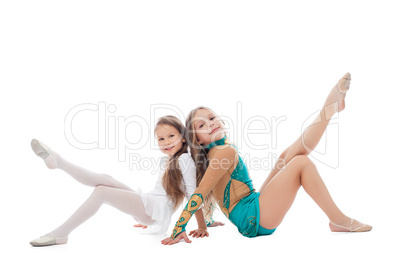Smiling sisters-gymnasts isolated on white