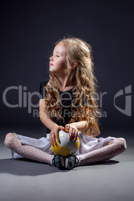 Cute curly-haired little girl posing with ball