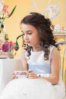 Lovely melancholy little girl drinking tea