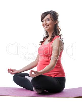 Smiling pretty pregnant woman meditating in studio