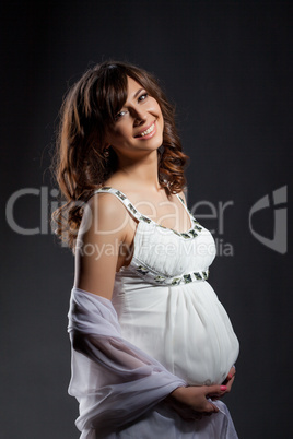 Happy dark-haired pregnant woman smiling at camera