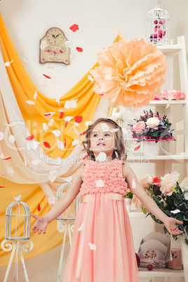 Fashionable little girl throwing petals in studio