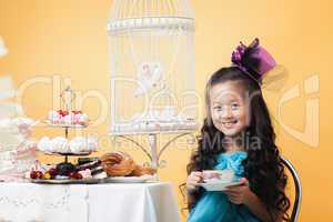 Smiling lovely girl drinking tea with sweet treats