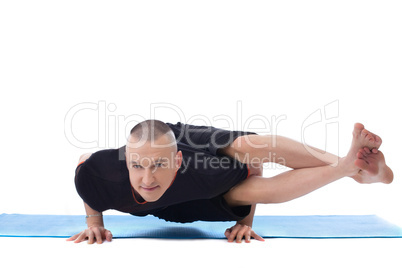 Smiling flexible man posing in difficult yoga pose