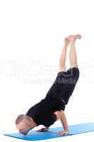 Athletic man doing yoga handstand in studio