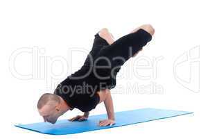 Focused on sporty man posing in complex yoga pose
