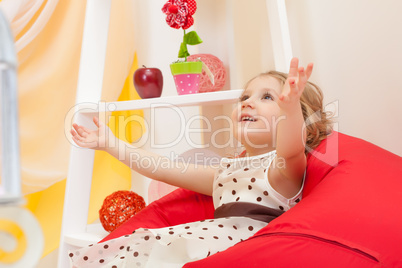 Image of merry beautiful child posing on ottoman