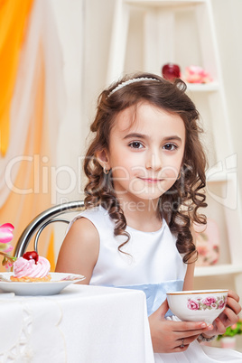 Beautiful brown-eyed girl drinking tea with sweets