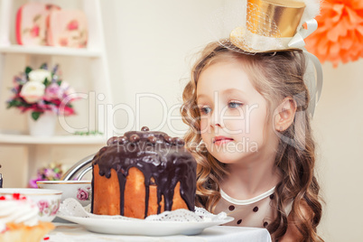 Adorable little girl looks thoughtfully at cake