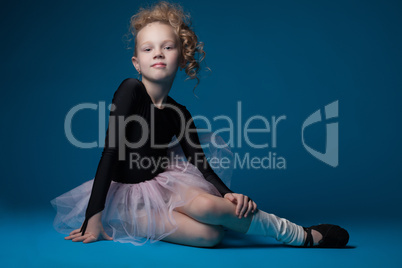 Cute curly ballet dancer posing on blue background