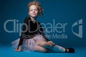 Cute curly ballet dancer posing on blue background
