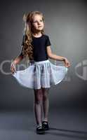 Pretty little girl posing straightened her skirt