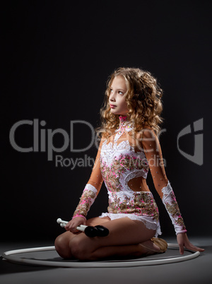 Beautiful young gymnast posing with mace and hoop