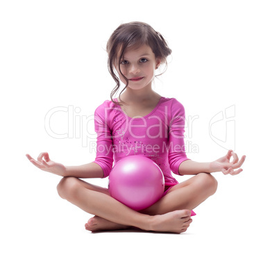 Smiling gymnast posing in lotus position with ball