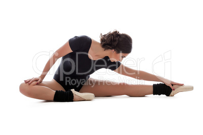 Young slender ballerina doing stretching in studio
