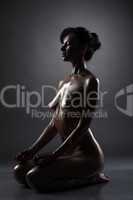 Attractive swarthy naked woman meditates in studio