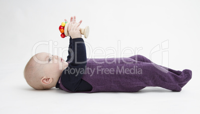 baby lying on his back with toy