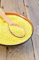 Corn grits in bowl with spoon on board