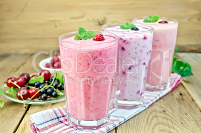 milkshakes with berries in glass on board