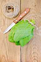 Spinach on board with knife and twine