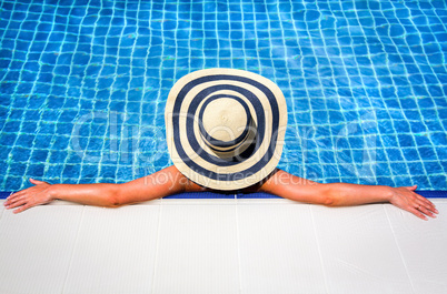 woman in straw hat relaxing swimming pool