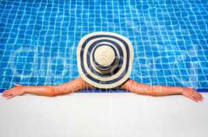 woman in straw hat relaxing swimming pool