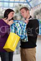 junge frau zeigt ihrem freund ein hemd beim einkaufen in shoppin