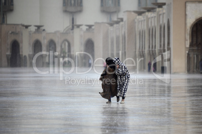 Two Moroccans run through the rain