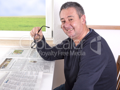 man sitting by the window and reading newspaper