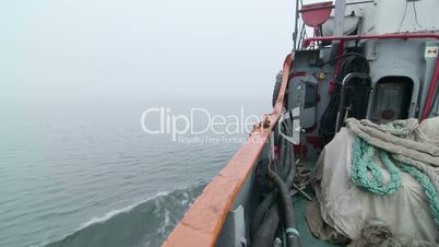 Fishing boat moving forward in the misty sea