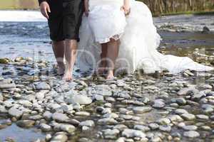 Bride and groom walking through water
