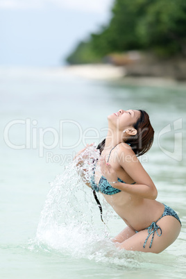 young filipina woman splashing in the sea