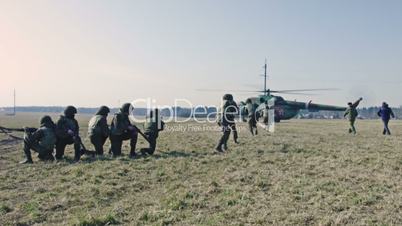 Soldiers with guns are running to  helicopter.