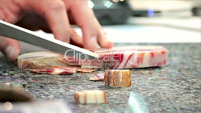 man chef cuts smoked pancetta bacon