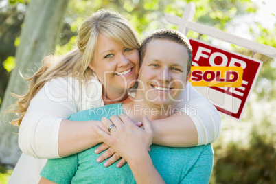 Happy Couple In Front Sold Real Estate Sign