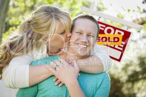 Happy Couple In Front Sold Real Estate Sign