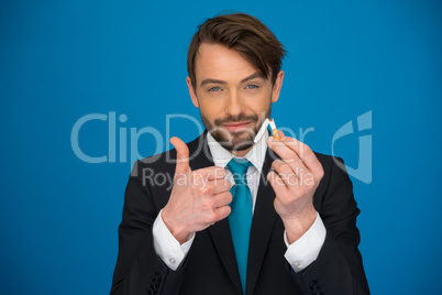 handsome businessman holding broken cigarette and e-cigarette in the other hand