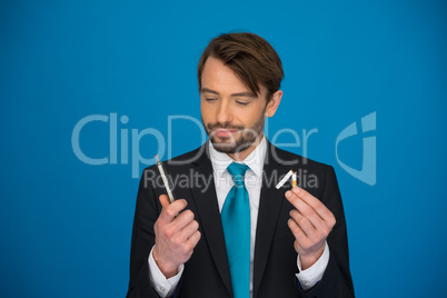 handsome businessman holding broken cigarette and e-cigarette in the other hand