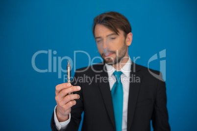 businessman with e-cigarette wearing suit and tie on blue