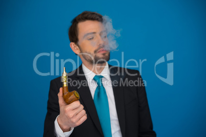 businessman with e-cigarette wearing suit and tie on blue