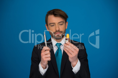 businessman holding e-cigarette and e-liquid on blue