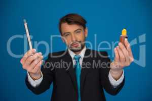 businessman holding e-cigarette and e-liquid on blue