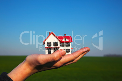 Female hand holding model of residential building