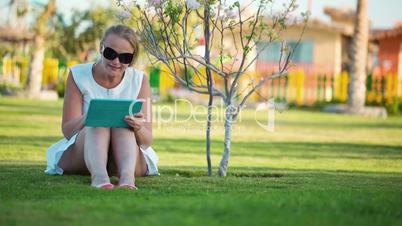 Beautiful woman sitting barefoot on a lawn