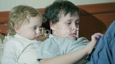 Two young children playing with a tablet